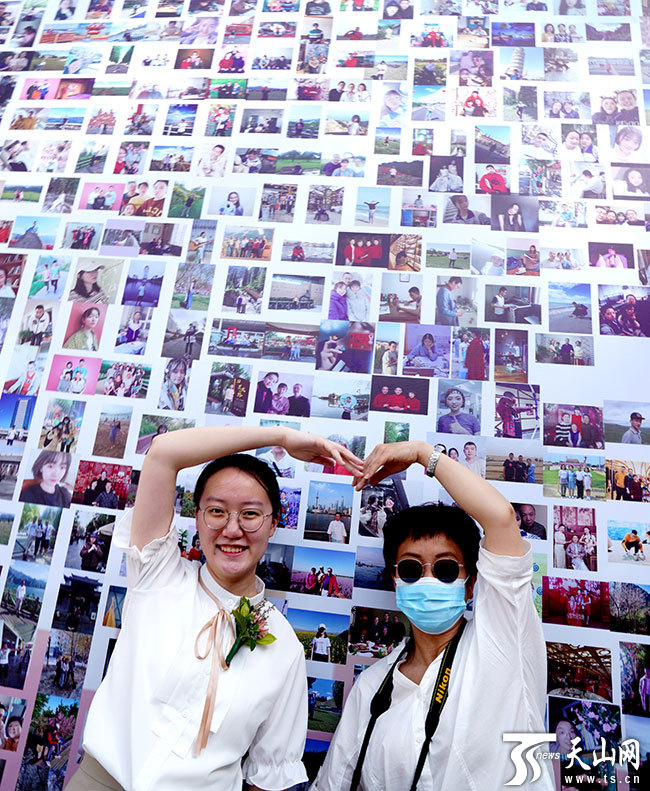 高三(9)班高依敬同学在成人礼照片墙中找到自己的照片,并和妈妈一起