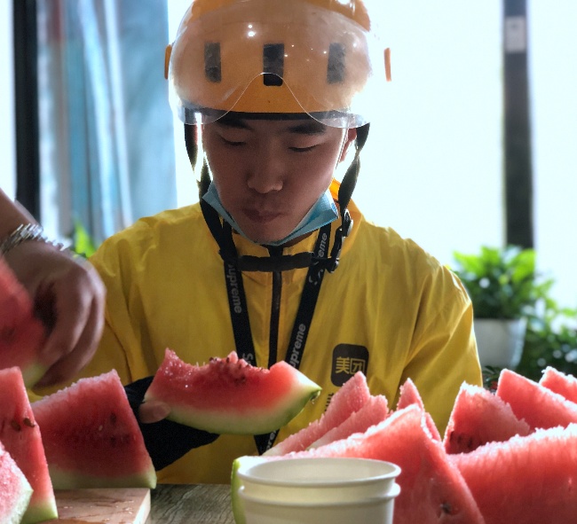 7月5日,乌鲁木齐市一名送餐员在外卖站点吃西瓜解渴.